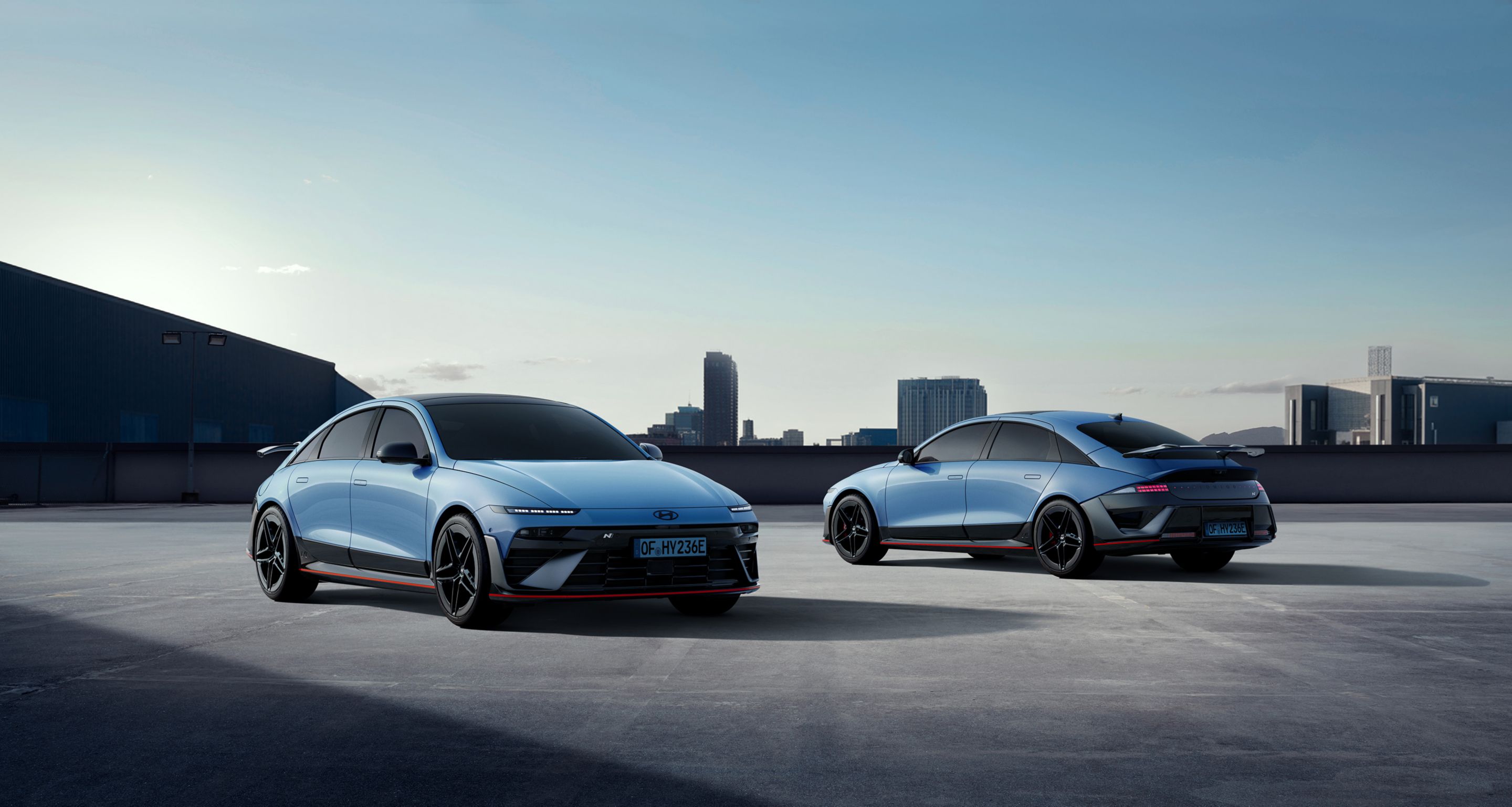 Two Hyundai IONIQ 6N cars parked on a rooftop with a city skyline in the background.