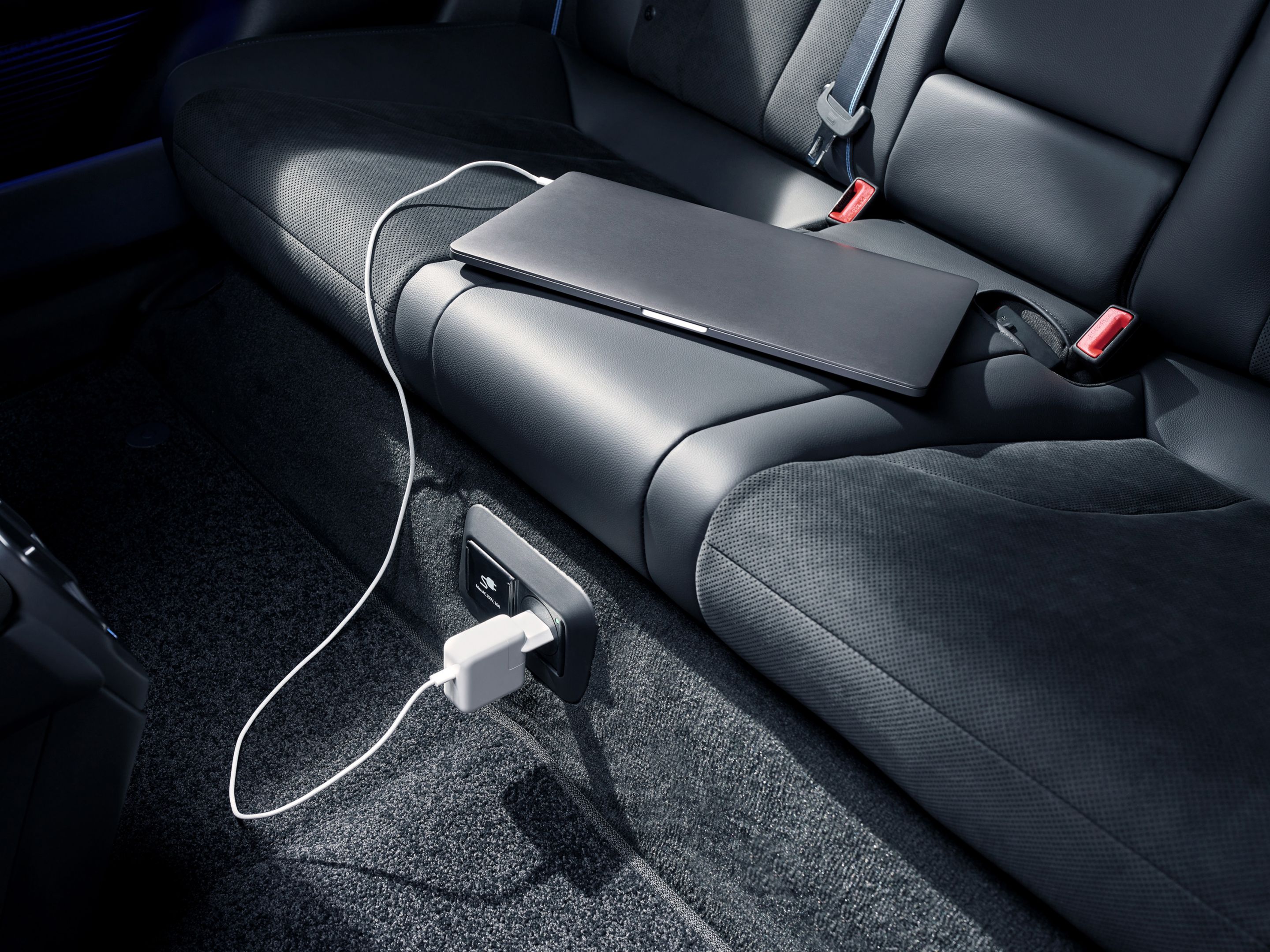 A Hyundai IONIQ 6 N hátsó ülésénél kialakított aljzatból laptop töltődik.