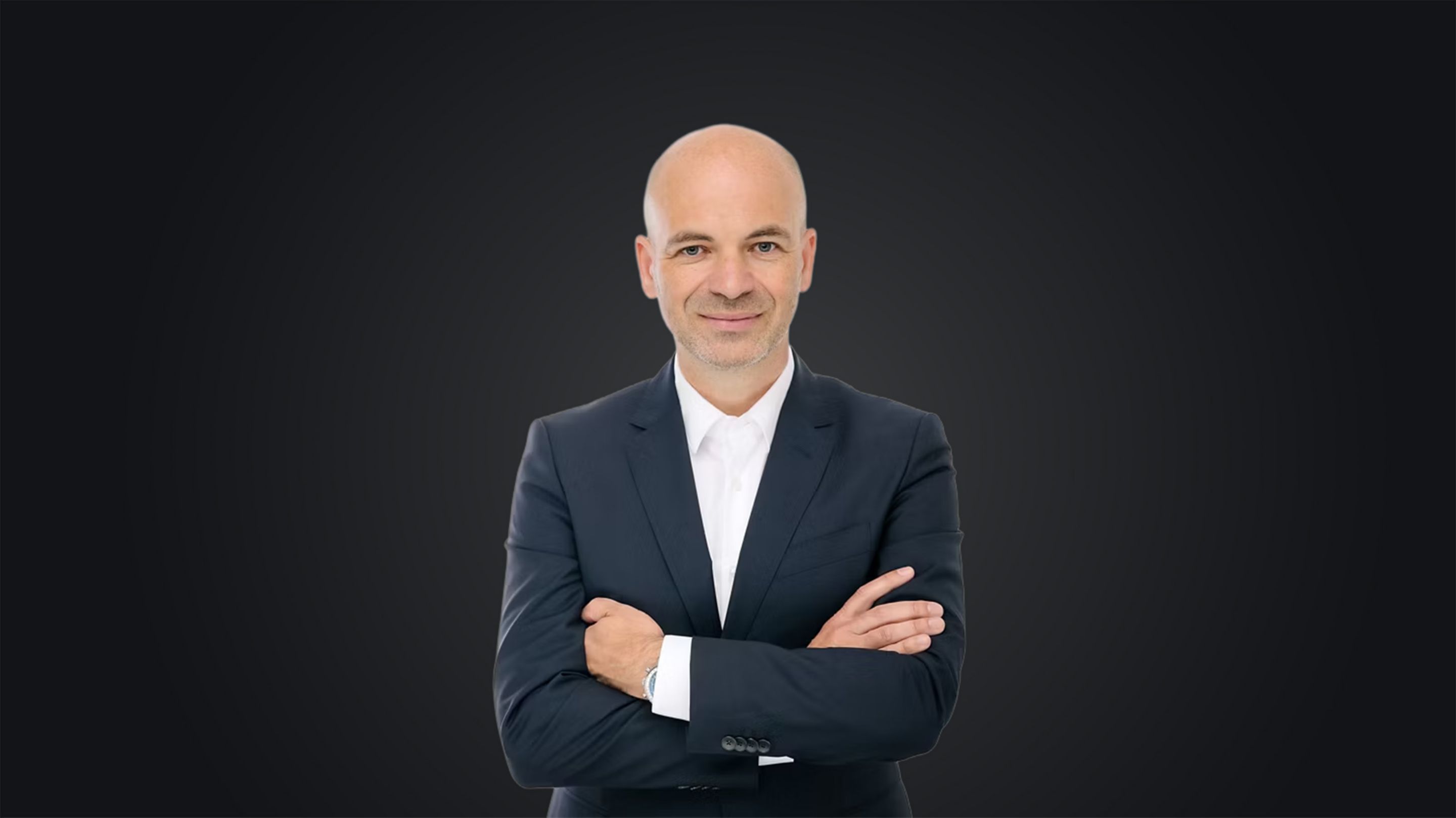 Manfred Harrer, a Genesis és a nagy teljesítményű fejlesztési osztály vezetője összefont karral áll sötét háttér előtt.